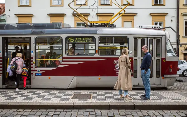 A senior citizen and her younger companion board a tram in central Prague.