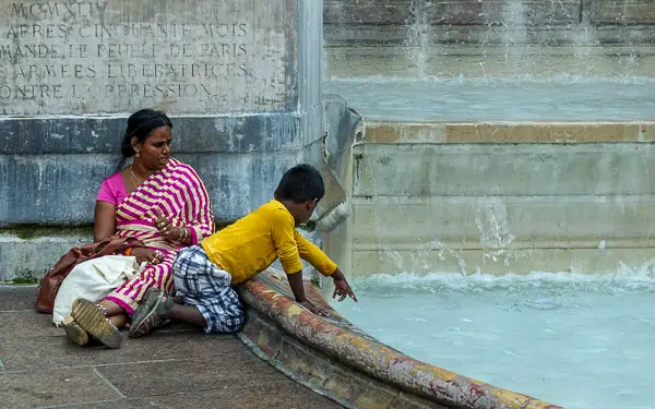 A woman and her son rest near a fountain in Paris.