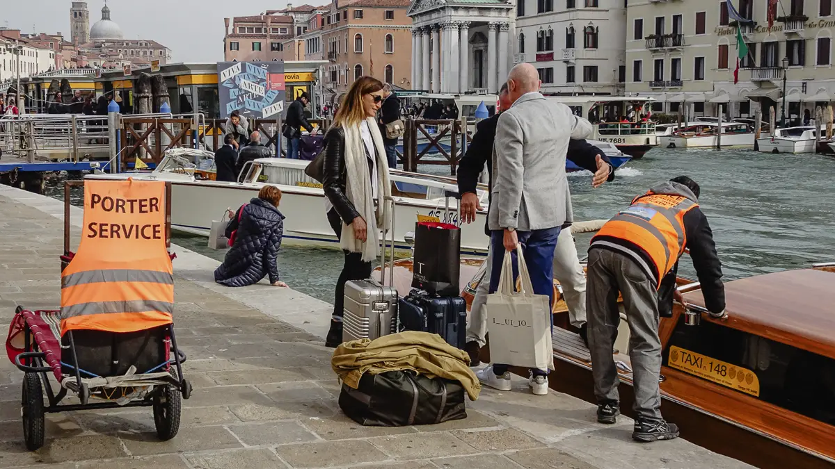 A baggage porter loads luggage into a water taxi at Venice's Santa Lucia Railroad Station.