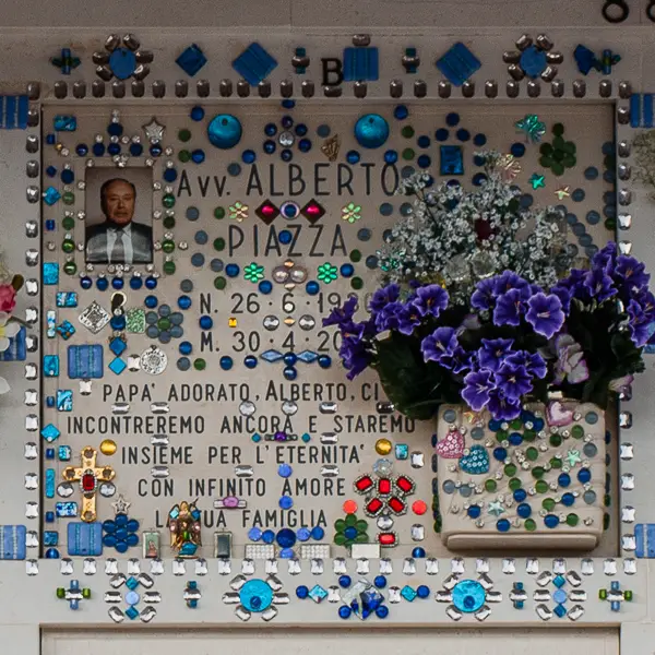 The niches in San michele's outdoor mausoleums are often decorated with photos, flower vases, and other items. This niche is covered in glass mosaic.