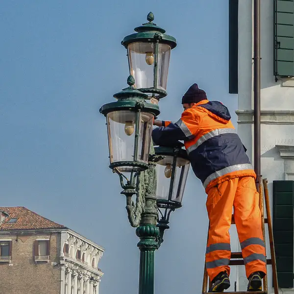 A municipal worker changes a lightbulb in a Venice streetlamp.