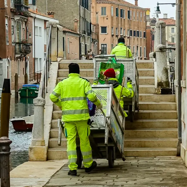Spazzini, or sanitation workers, hump their garbage and recycling carts over a bridge in Venice's Cannaregio district.