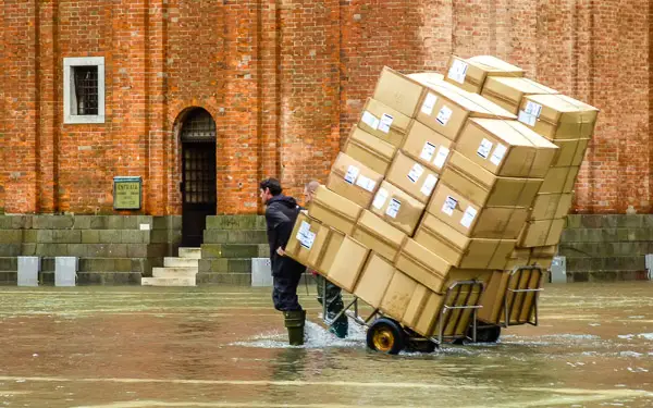 Delivery man with packages during an 'acqua alta' or flood tide in Venice's Piazza San Marco.